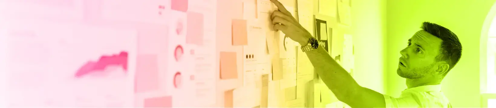 Person vor einer Wand mit Post-its, Notizen und Ausdrucken. Bild ist mit einem Farbverlauf aus consus healthcare akademie Farben eingefärbt.